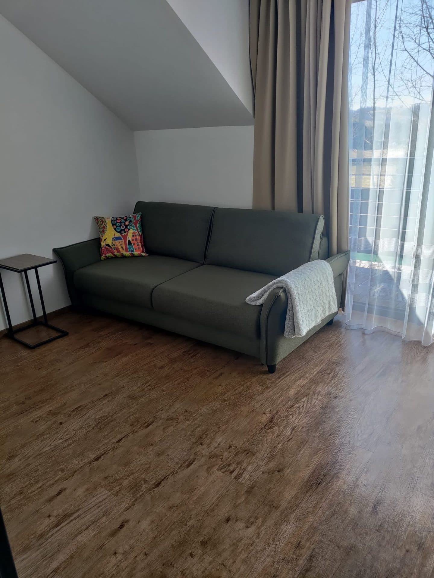 Obývací pokoj s rozkládací pohovkou a vstupem na terasu